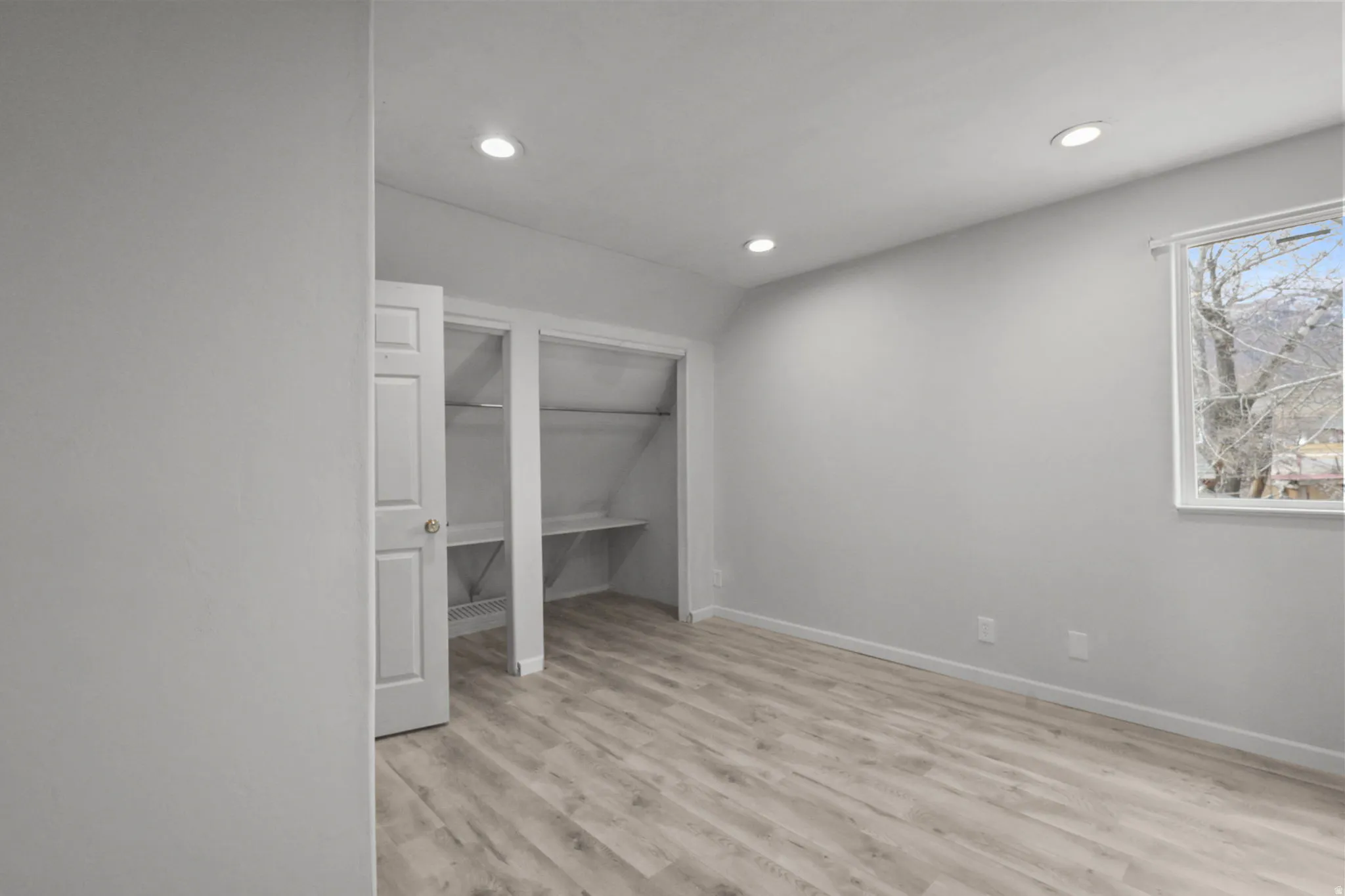 Unfurnished bedroom featuring light wood finished floors, recessed lighting, a closet, and lofted ceiling