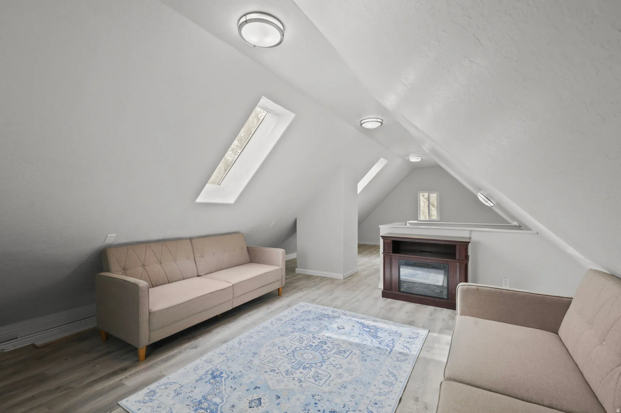 Living area with light wood finished floors, a skylight, and a textured ceiling