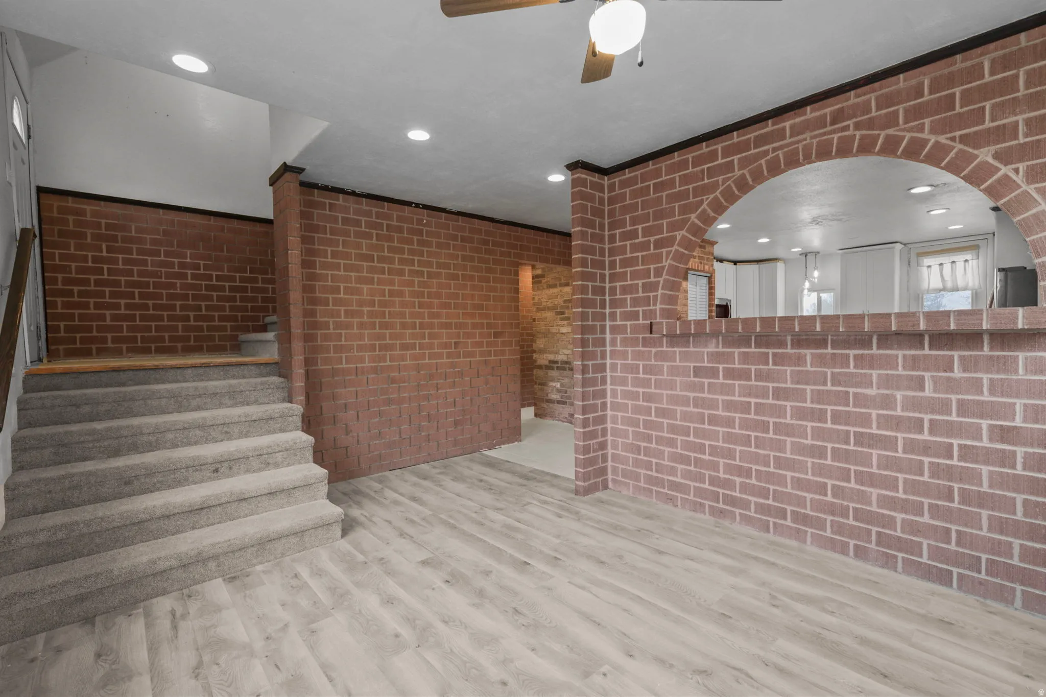 Unfurnished living room with brick wall, recessed lighting, a ceiling fan, and light wood finished floors