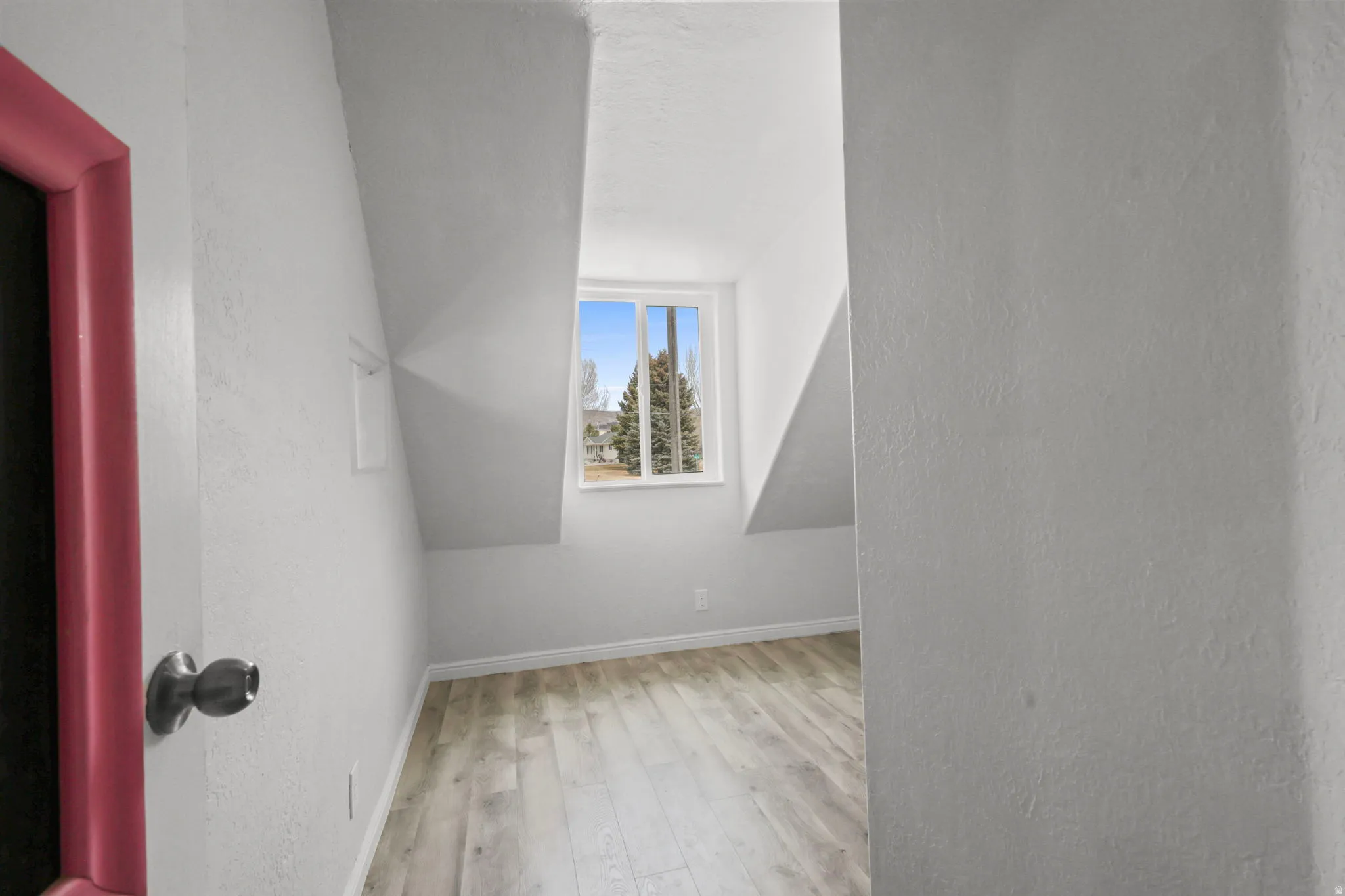Additional living space with light wood finished floors and a textured wall