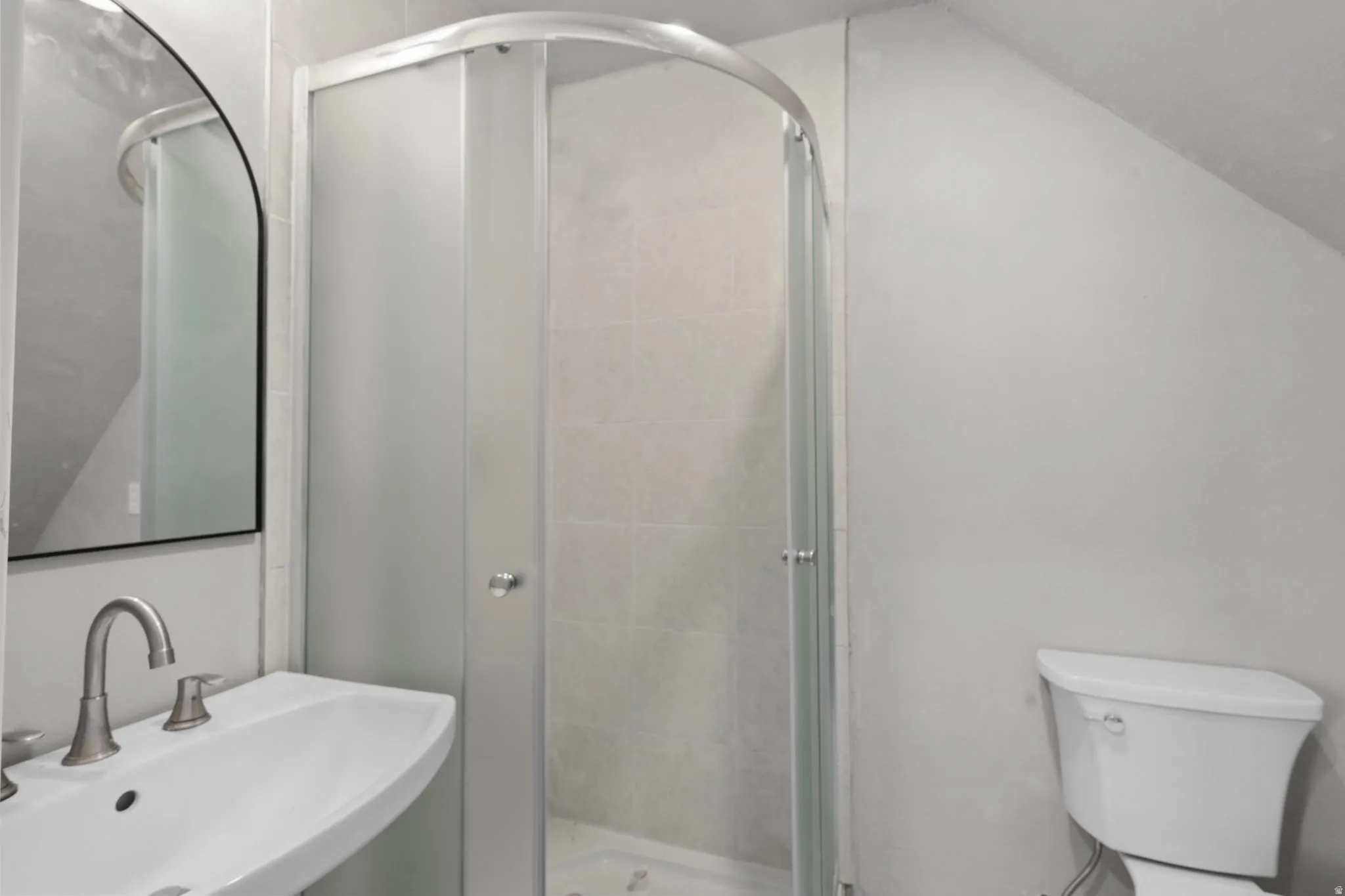Bathroom with a shower stall and lofted ceiling