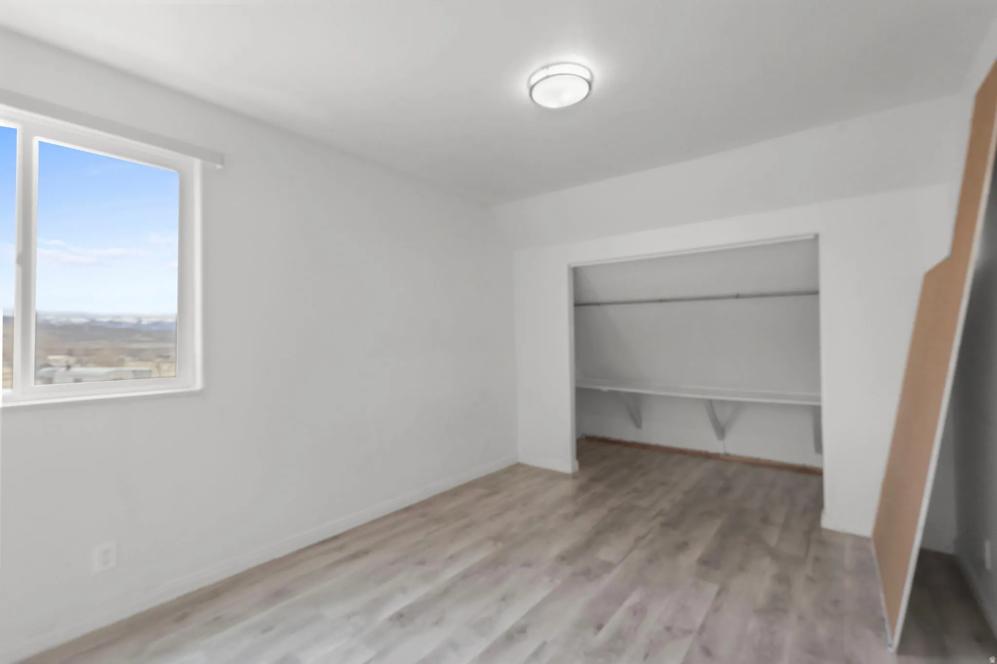 Unfurnished bedroom with lofted ceiling, light wood-style floors, and a closet