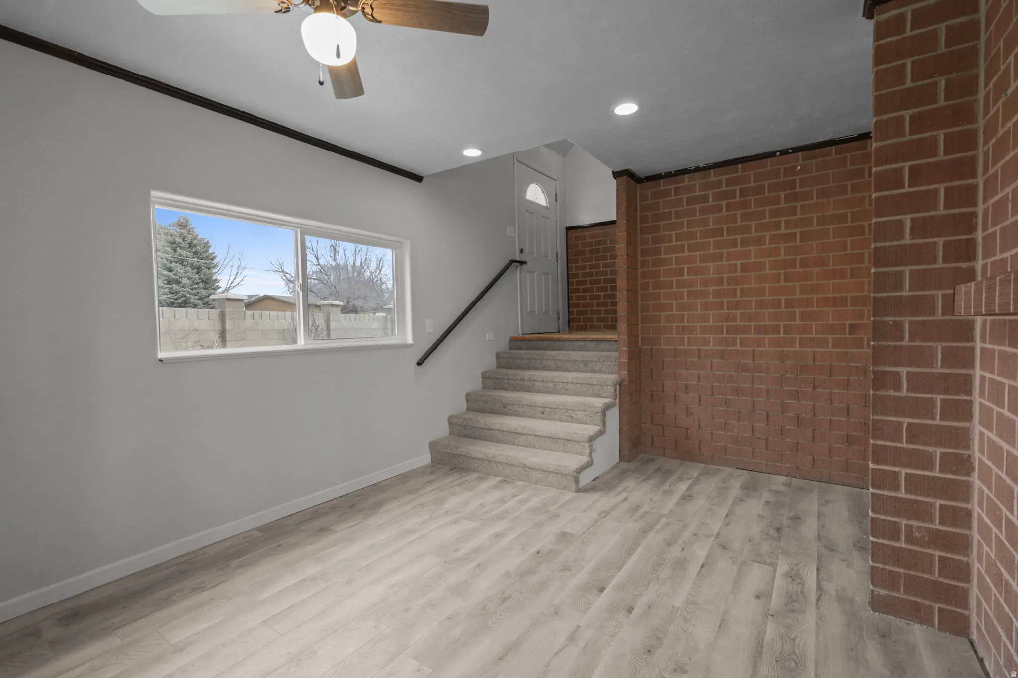 Staircase with brick wall, wood finished floors, recessed lighting, ceiling fan, and crown molding