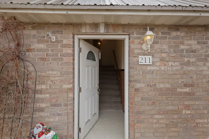 View of exterior entry with brick siding and a metal roof