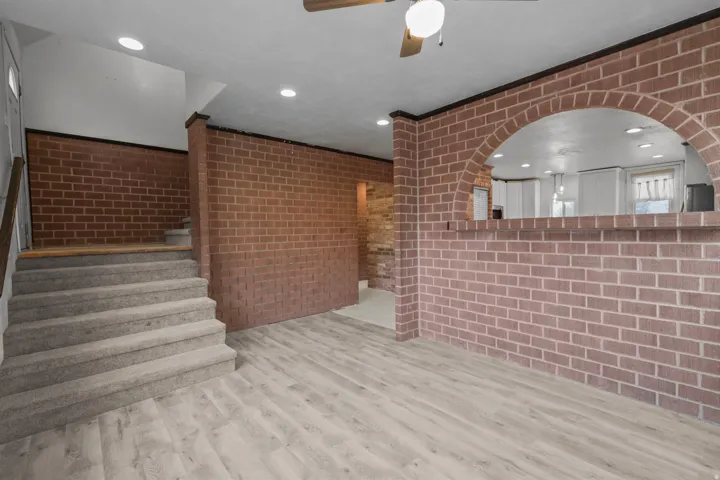 Unfurnished living room with brick wall, recessed lighting, a ceiling fan, and light wood finished floors