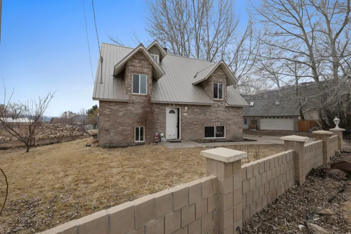 View of side of home with a metal roof, brick siding, a patio area, and a detached garage