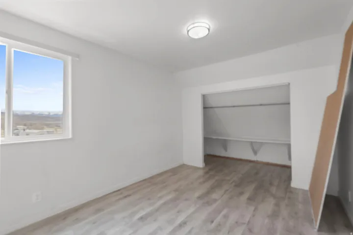 Unfurnished bedroom with lofted ceiling, light wood-style floors, and a closet