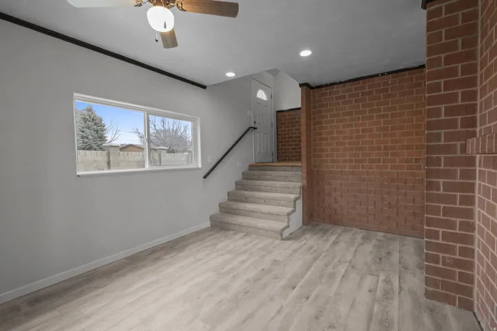Staircase with brick wall, wood finished floors, recessed lighting, ceiling fan, and crown molding