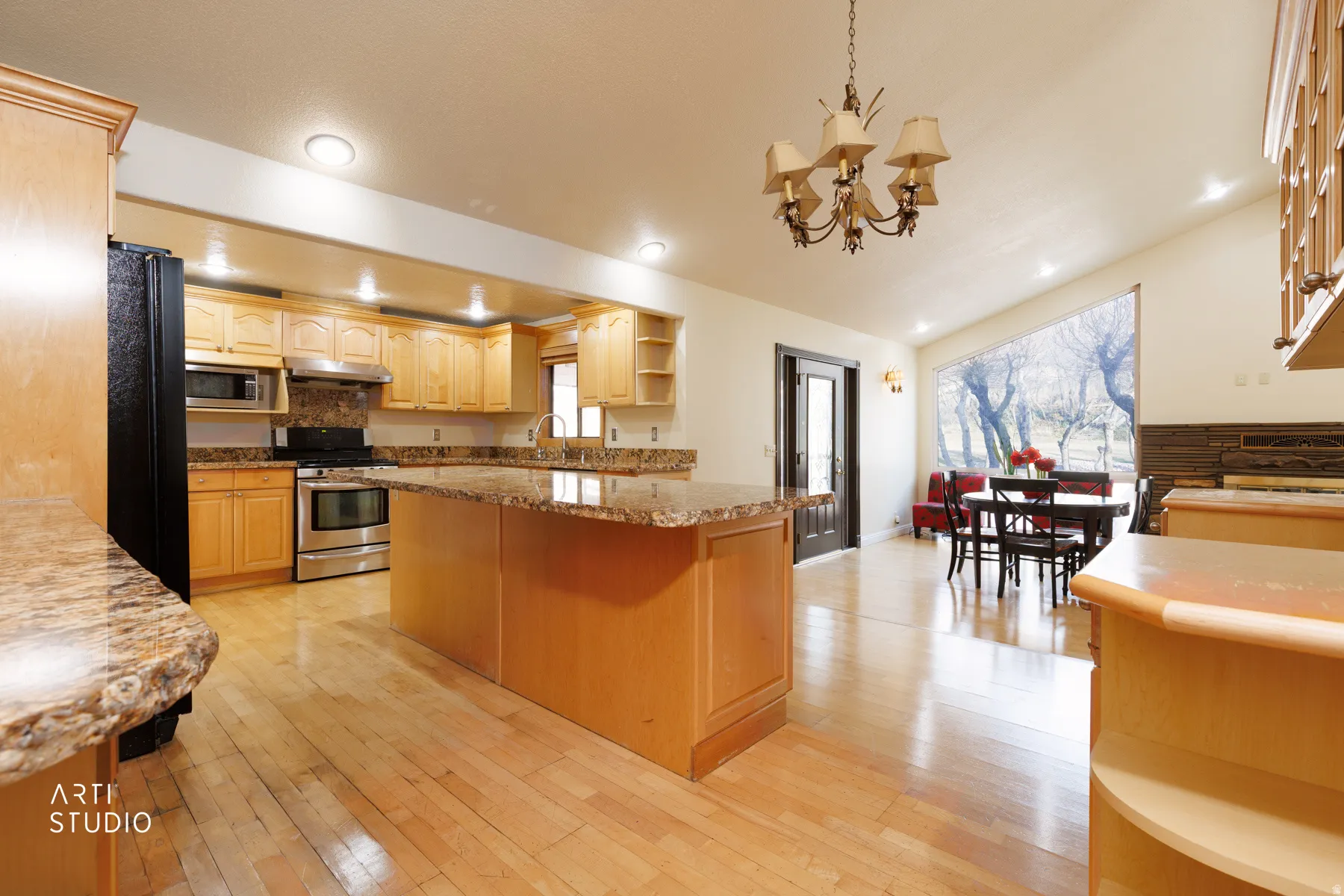 Kitchen with open shelves, light wood finish cabinets, stainless steel appliances, light stone counters, and light wood-style floors