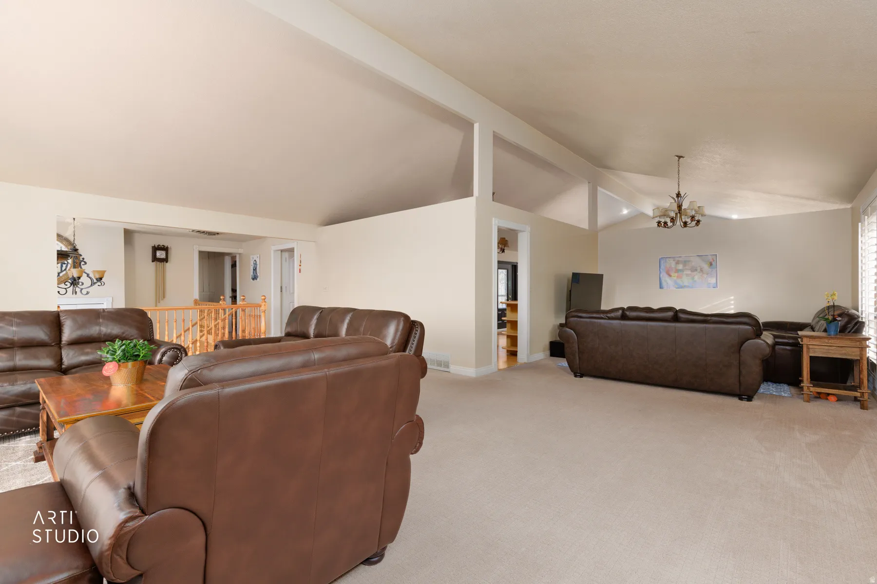 Living area featuring beamed ceiling, suspended lighting, and light carpet