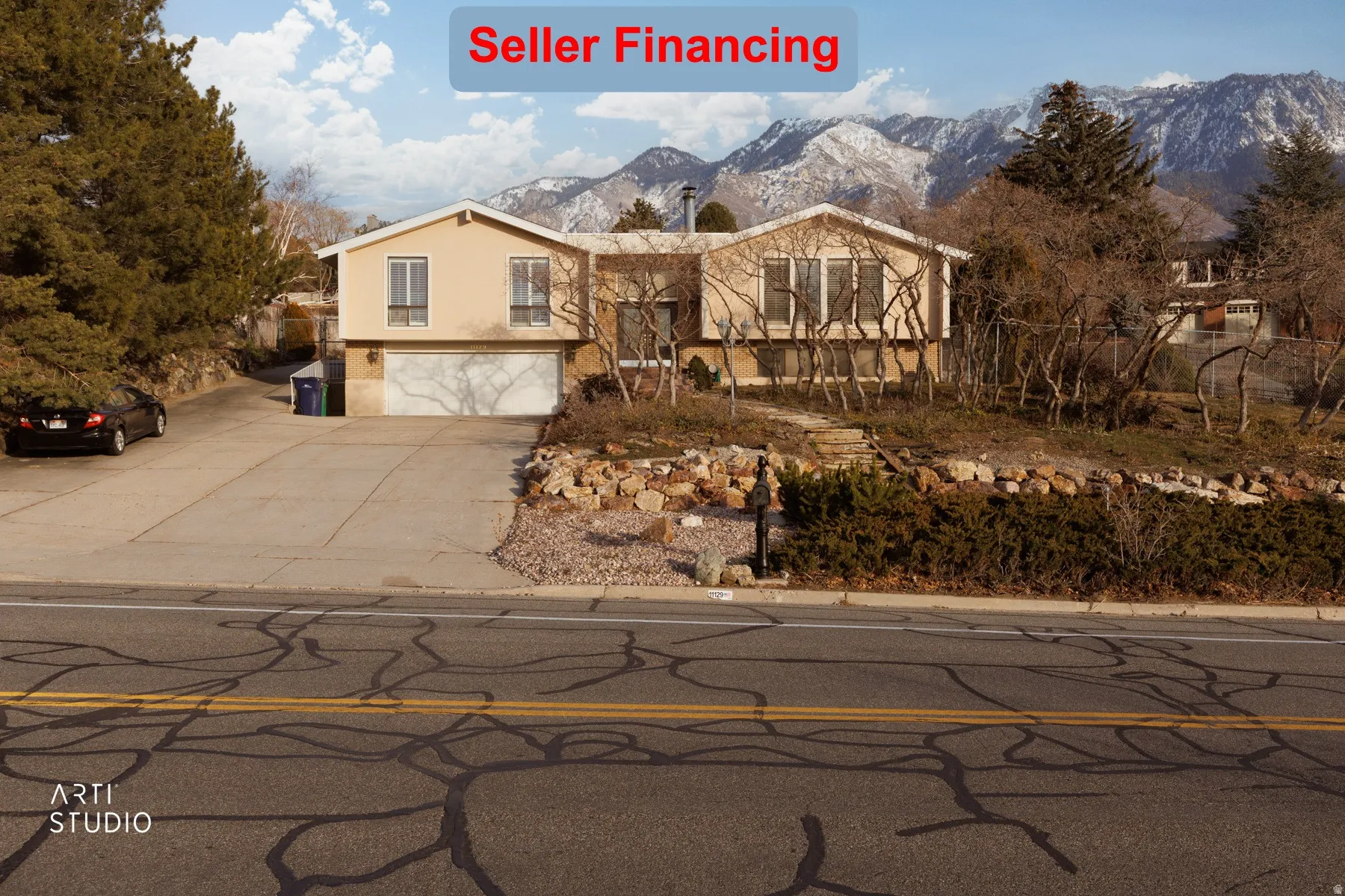 Bi-level home featuring a garage, a mountain view, stucco siding, and driveway