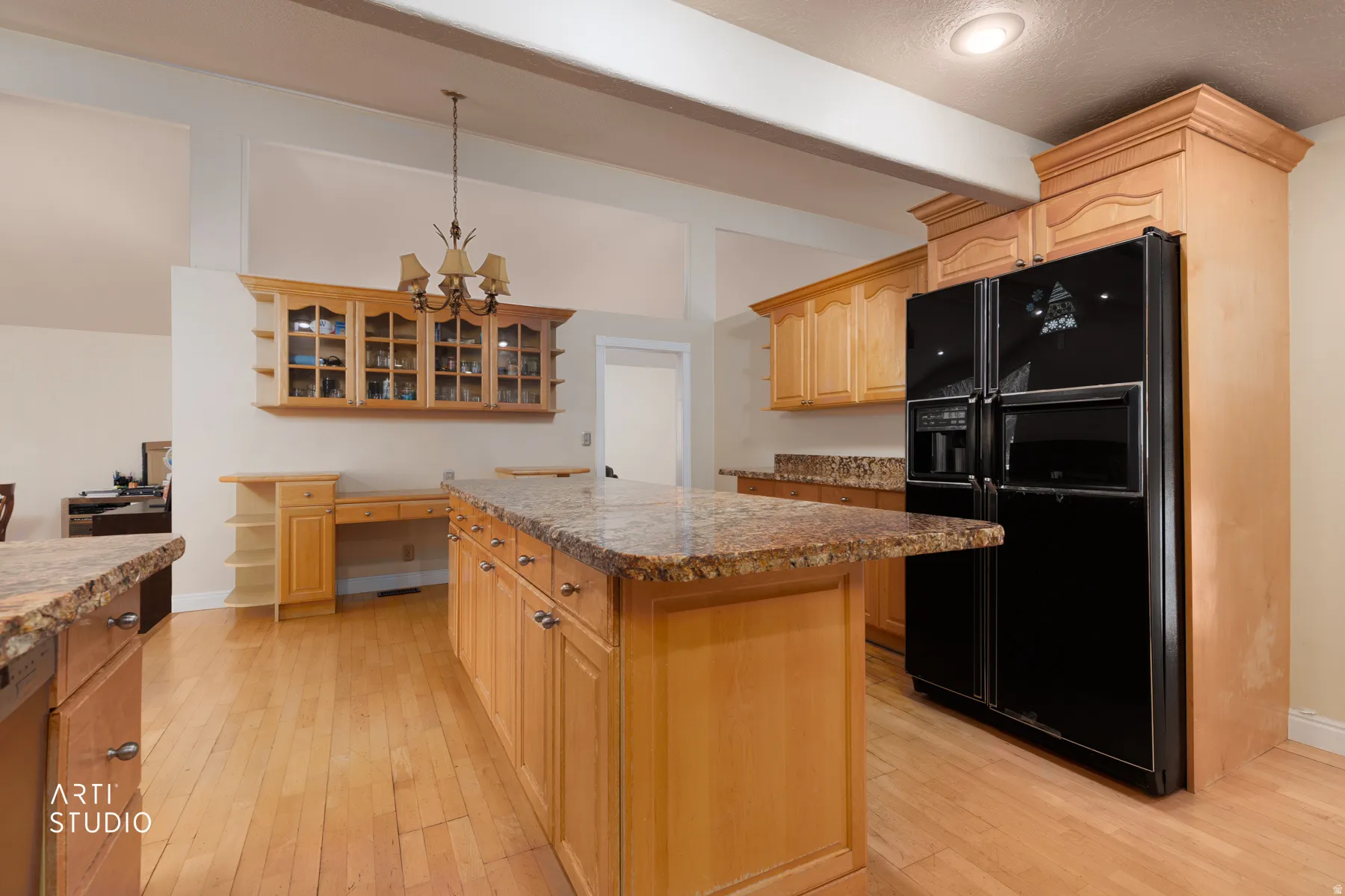 Kitchen featuring black fridge with ice dispenser, light wood finish cabinets, light wood-type flooring, glass insert cabinets, and a kitchen island