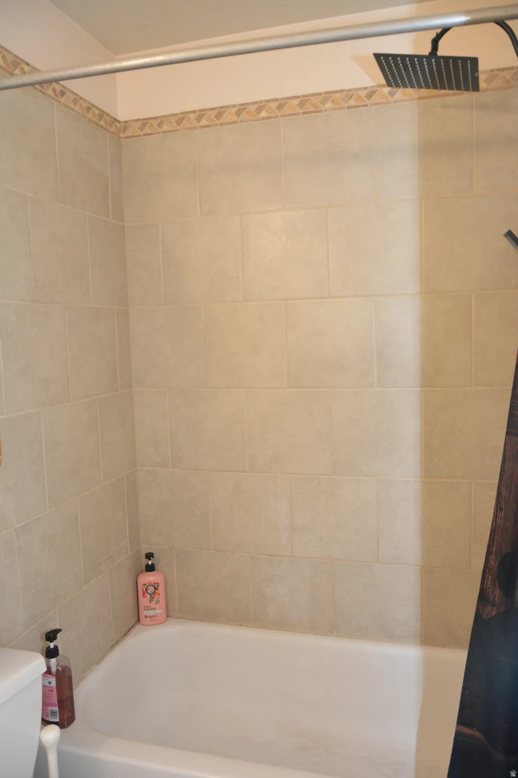 Bathroom featuring toilet and shower / bath combination with curtain