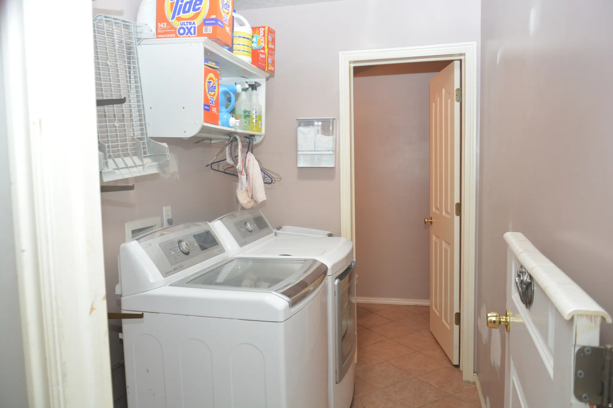 Laundry area featuring washing machine and clothes dryer and light tile patterned flooring