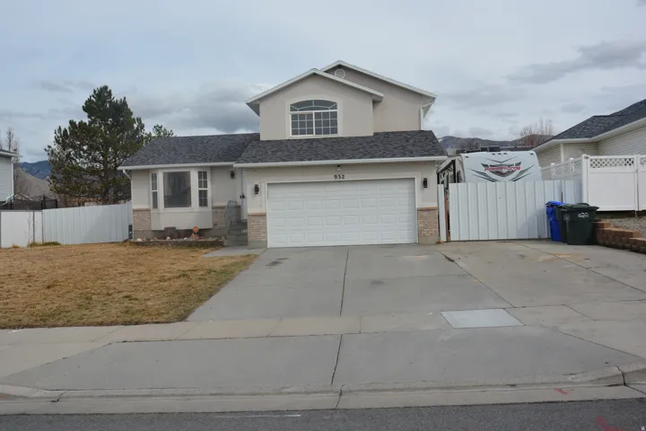Traditional home featuring stucco siding, a garage, concrete driveway, a gate, and a shingled roof