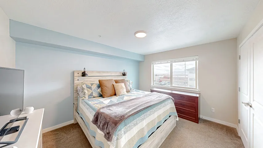 Bedroom featuring a closet, light colored carpet, and a textured ceiling