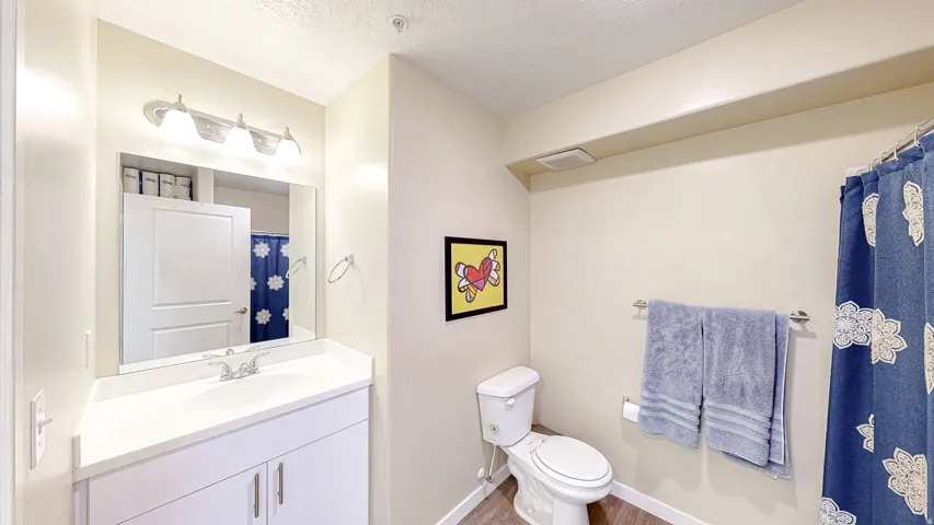 Full bathroom with vanity, a shower with curtain, a textured ceiling, and light wood-type flooring