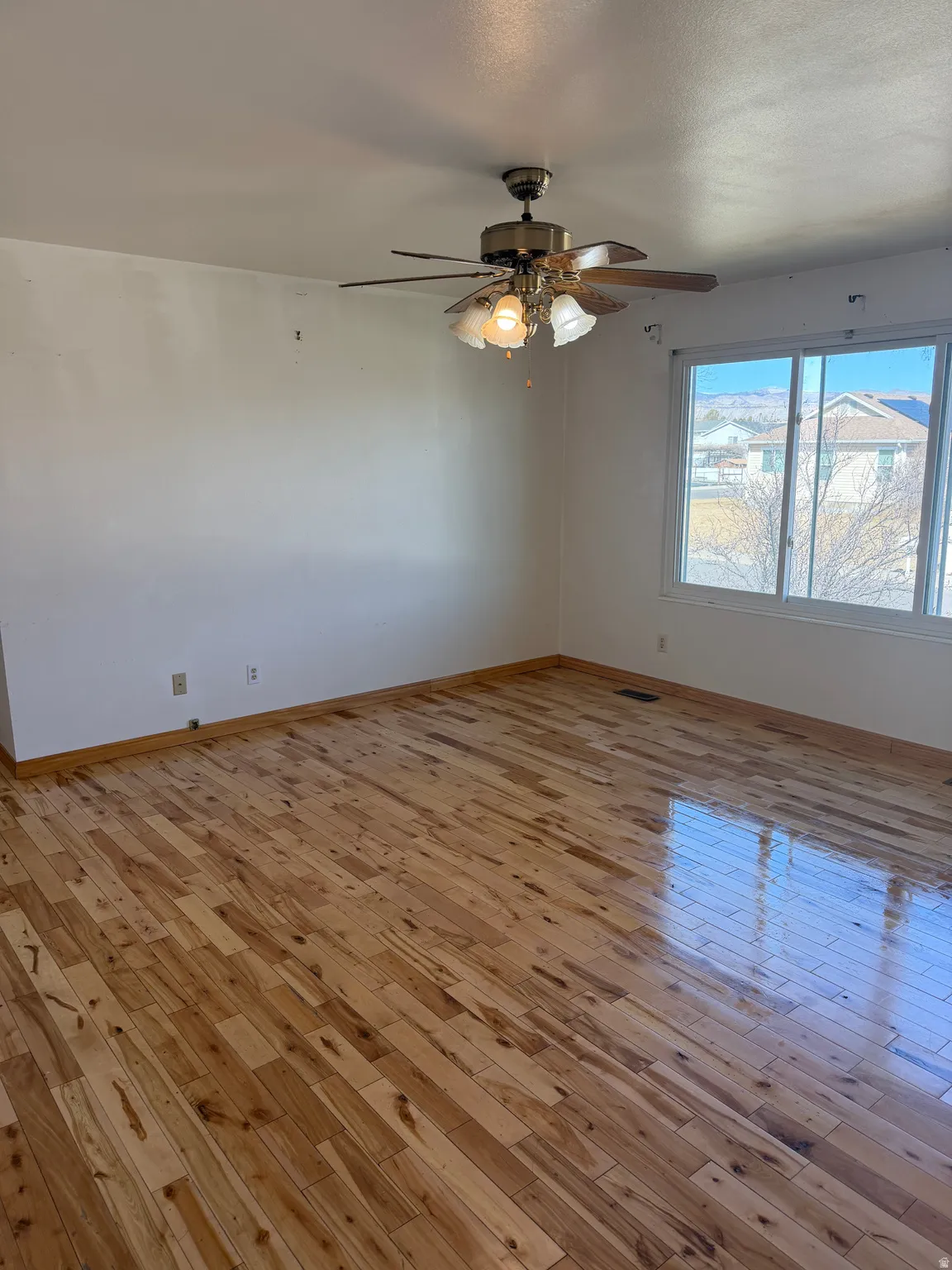 Unfurnished room with light wood-style flooring, a ceiling fan, and a textured ceiling