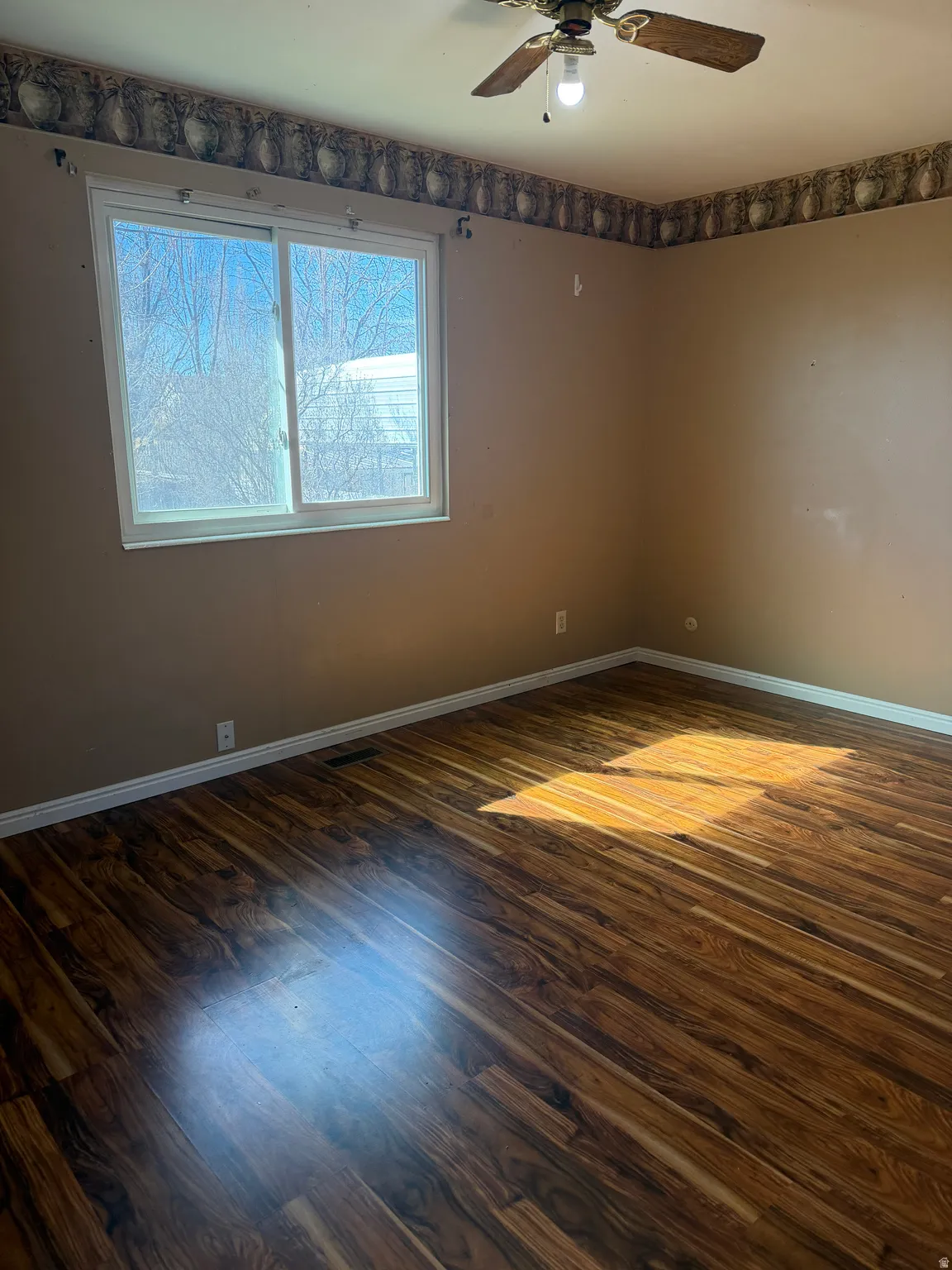 Empty room with dark wood-type flooring and a ceiling fan