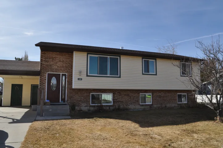View of front of house with brick siding, a front yard, an attached carport, and concrete driveway