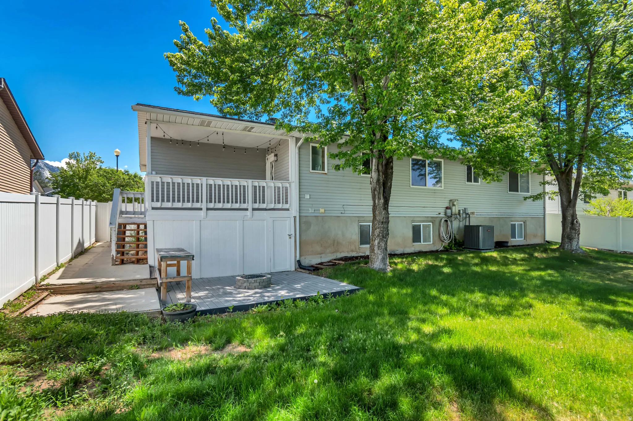 Expansive backyard featuring a manicured lawn, established trees, and a concrete patio