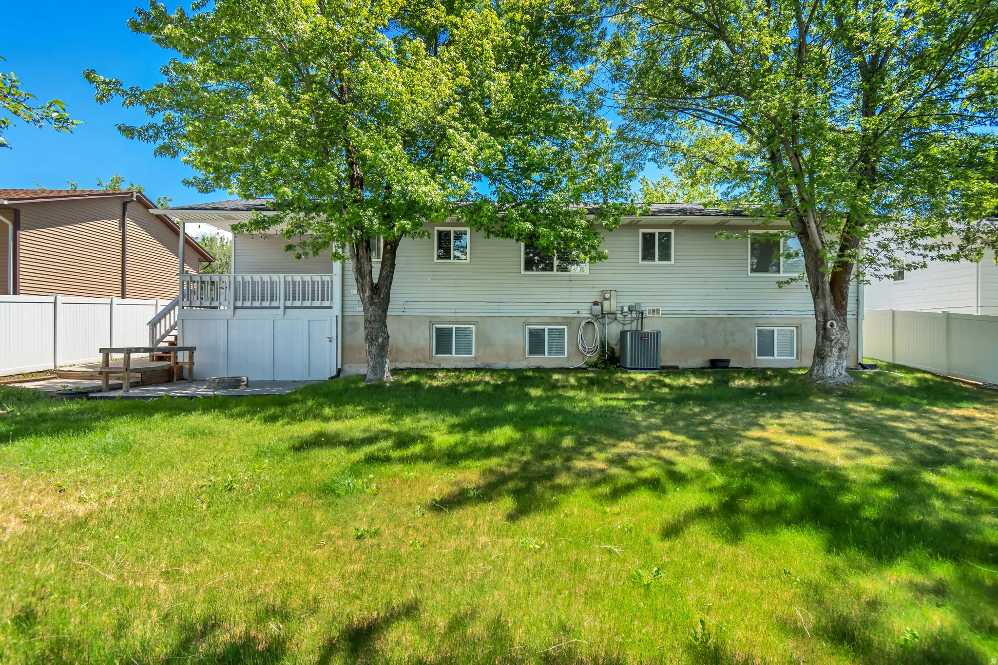 Expansive grassy backyard featuring mature trees providing natural shading