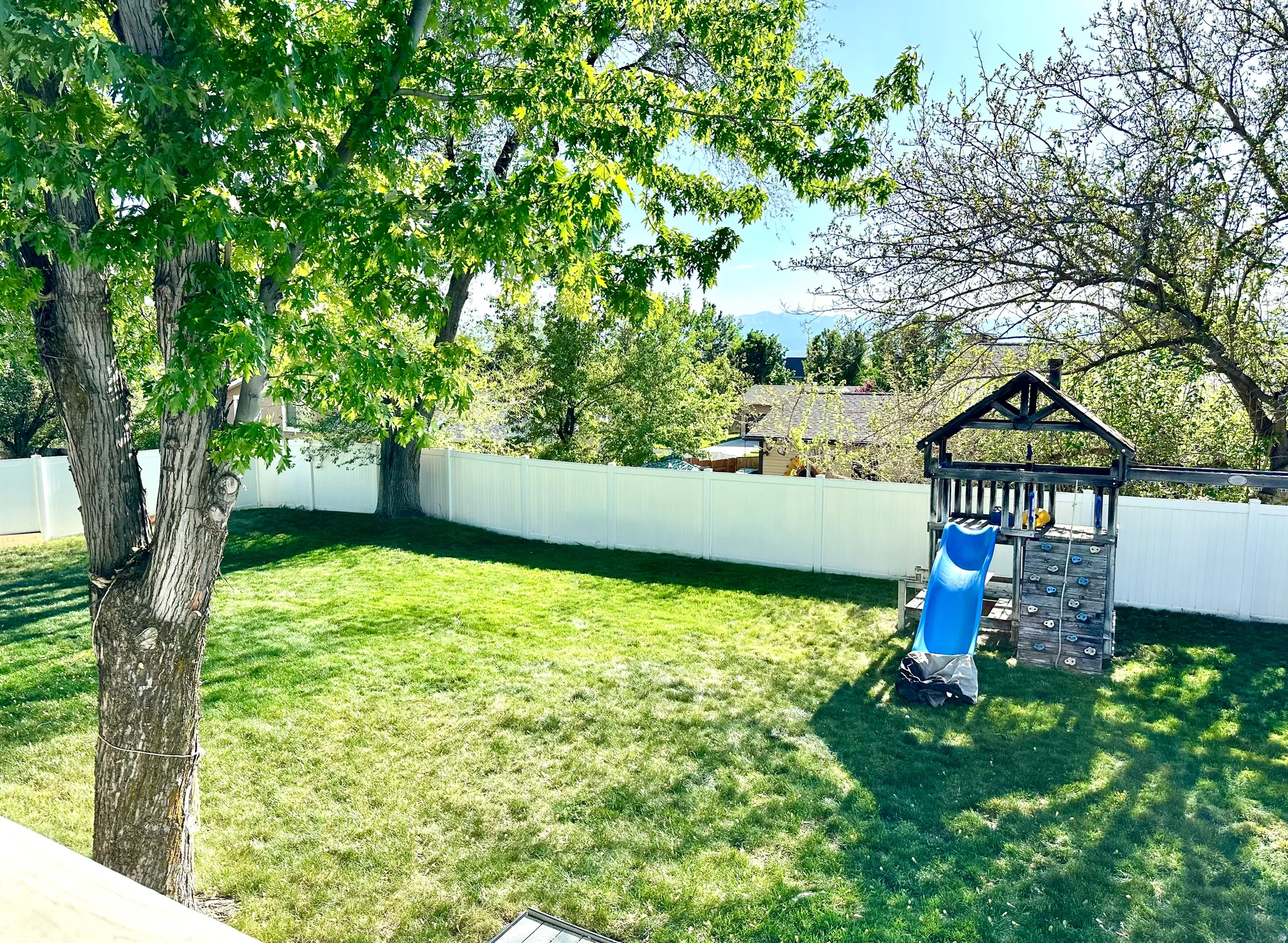Fenced backyard featuring a playground