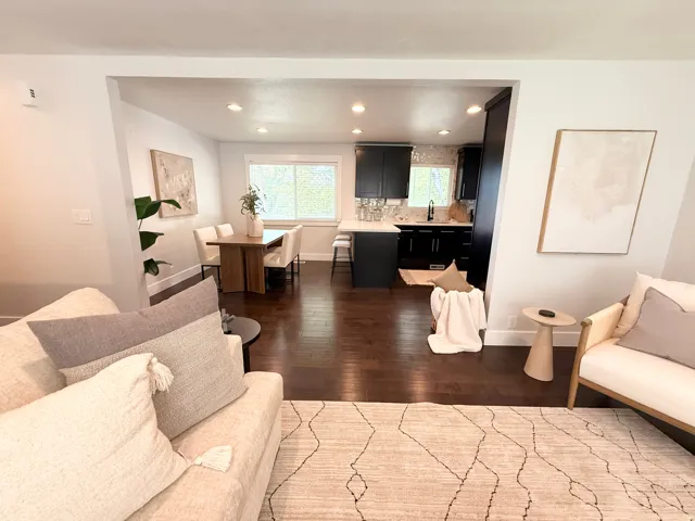 Hardwood flooring throughout, recessed lighting, and a kitchen featuring dark cabinetry, white countertops, and a tile backsplash