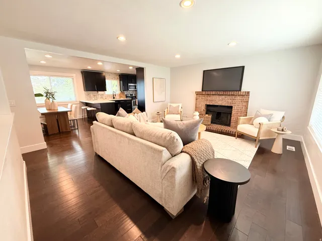 Open-concept living space featuring wood-finish flooring, recessed lighting, and a brick fireplace