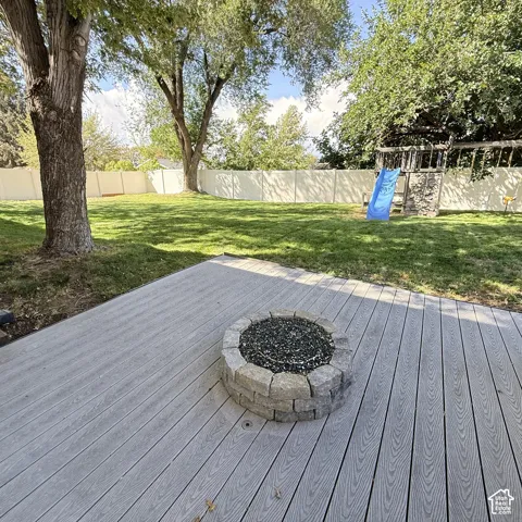 Expansive backyard with a composite deck, built-in stone fire pit, and mature trees