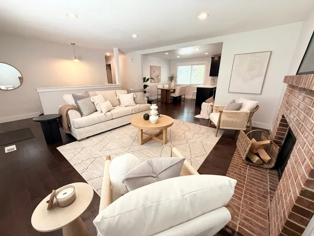 Brick fireplace with hearth, recessed lighting, dark wood-finish flooring, and a built-in half-wall