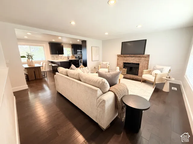 Open-concept living space featuring wood-finish flooring, recessed lighting, and a brick fireplace