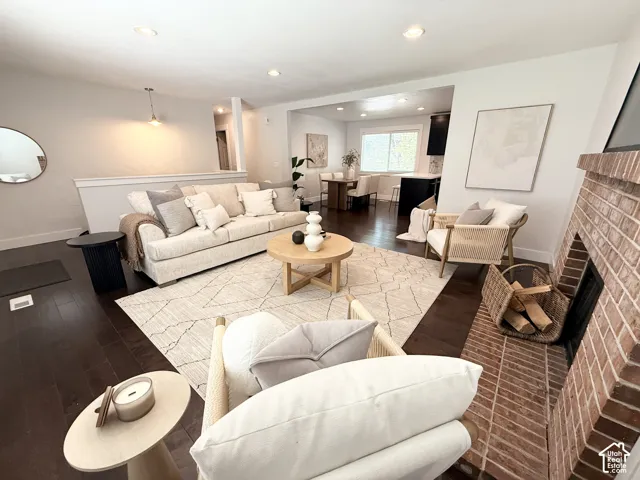 Brick fireplace with hearth, recessed lighting, dark wood-finish flooring, and a built-in half-wall