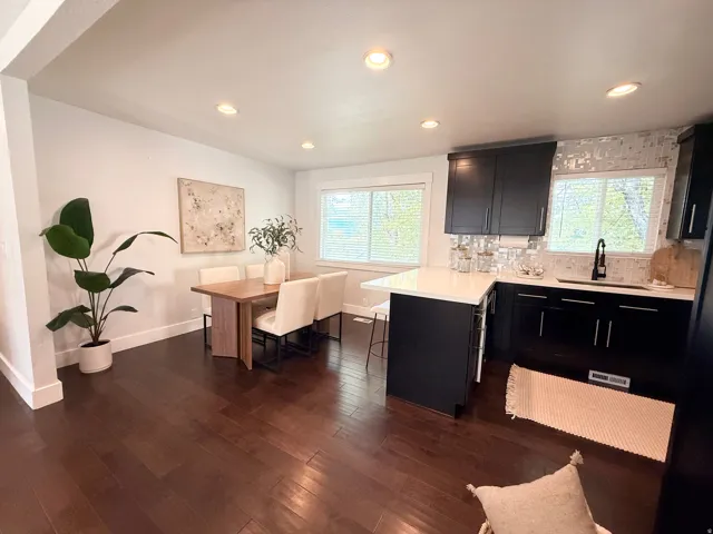 Kitchen and dining area featuring dark wood-finish flooring, recessed lighting, and white walls