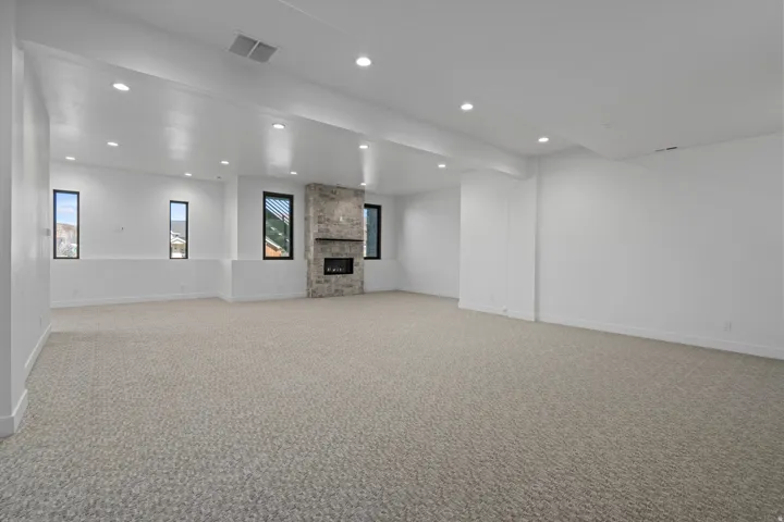 Lower level rec room with light carpet, recessed lighting, and a stone fireplace