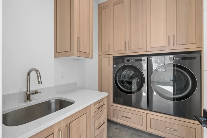 Upper level Laundry area with cabinet space, separate washer and dryer, and dark tile patterned floors