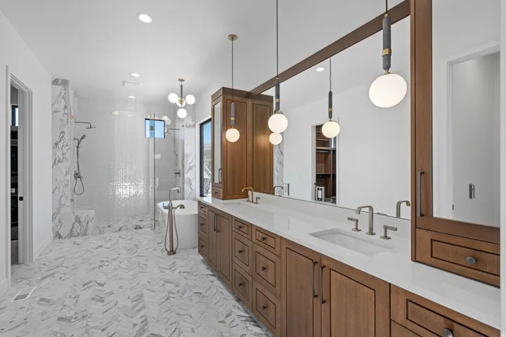 Primary Bathroom with double vanity, a walk in closet, a stall shower, and hanging lights
