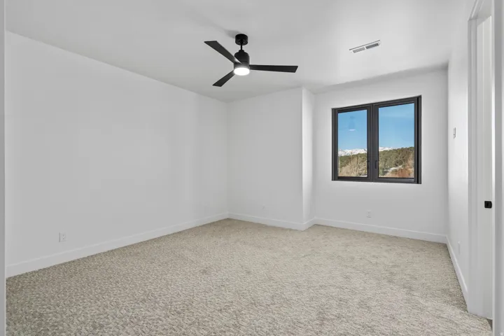Upstairs bedroom with light carpet and ceiling fan