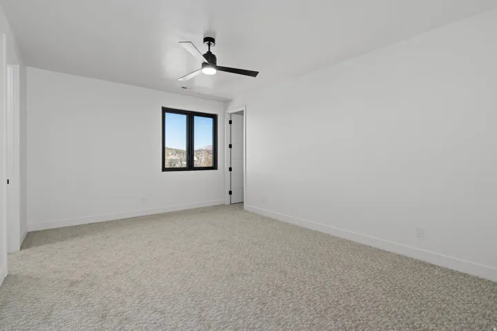Upstairs bedroom with light carpet and ceiling fan