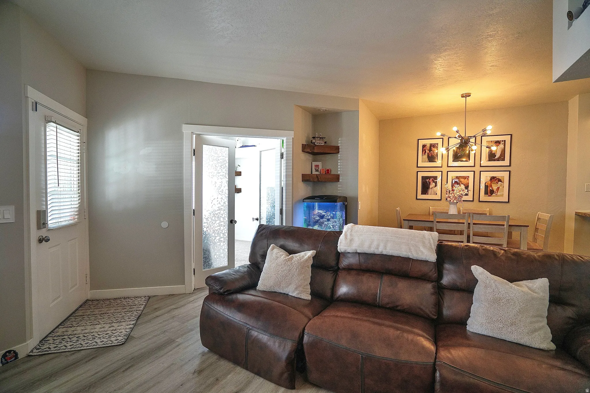 Living room with a chandelier, wood finished floors, and a textured ceiling