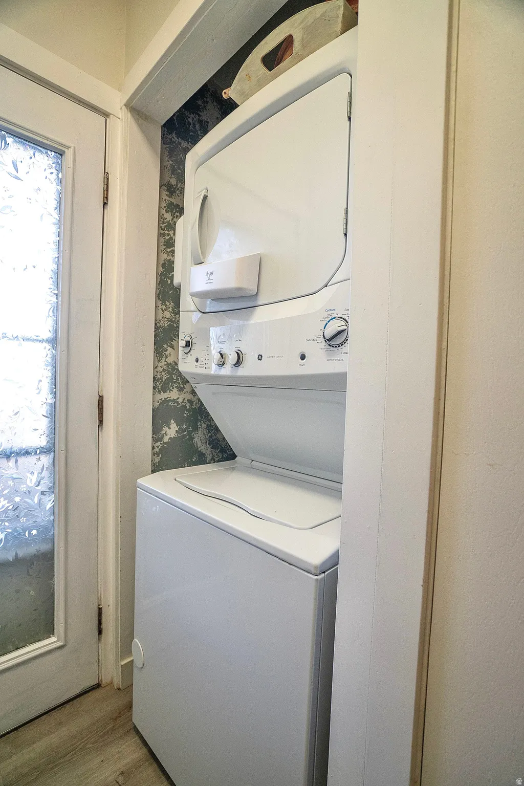 Laundry area featuring stacked washer and clothes dryer and wood finished floors