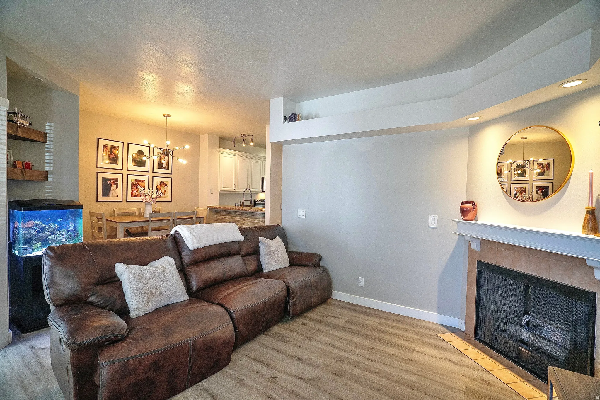 Living room featuring a tile fireplace, light wood-style flooring, and suspended lighting