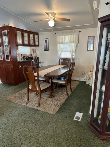 Carpeted dining space with a ceiling fan and a textured ceiling