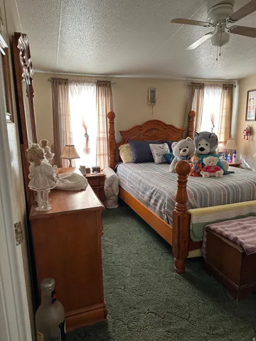 Bedroom with dark colored carpet, a ceiling fan, and a textured ceiling