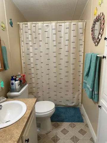 Bathroom featuring vanity, shower / tub combo, and a textured ceiling