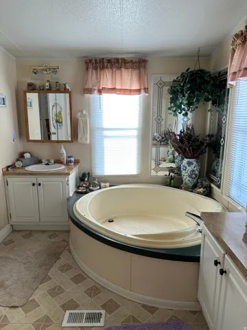 Full bath with two vanities, crown molding, a textured ceiling, and a bath