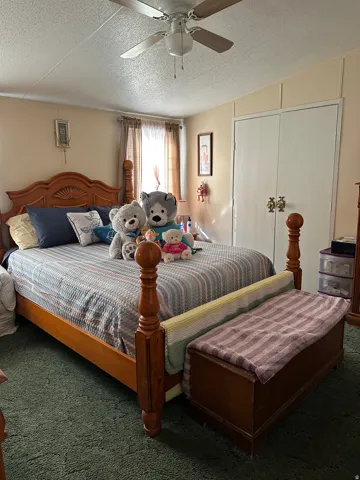 Carpeted bedroom featuring a textured ceiling, a closet, and a ceiling fan