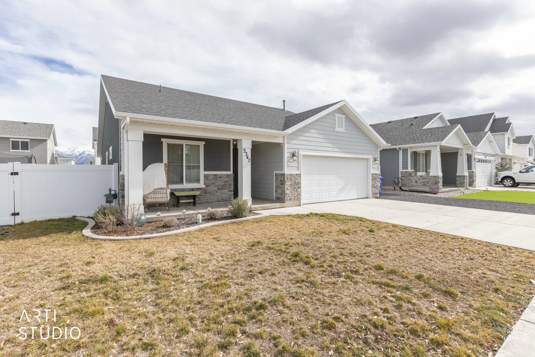 Craftsman house with covered porch, a garage, a gate, concrete driveway, and stone siding