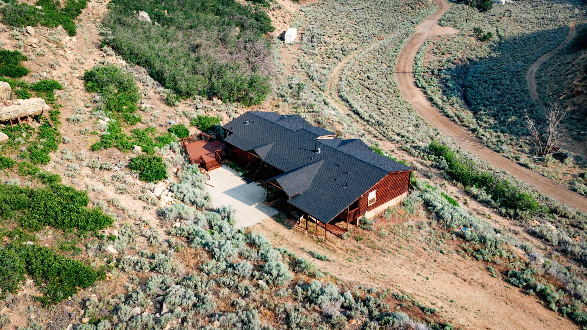 Wood-sided residence with dark shingle roofing, featuring a concrete driveway and multiple wooden deck areas
