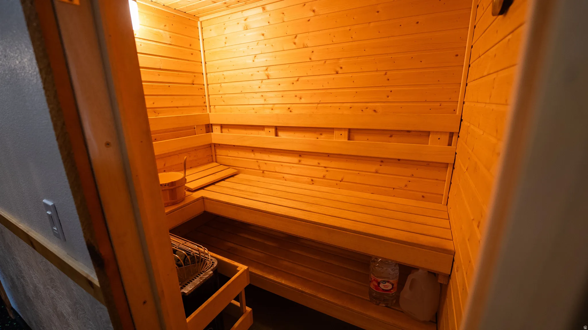 Wood-paneled sauna featuring built-in wooden benches and an illuminated interior